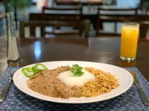 a plate of food with noodles and a glass of orange juice at Hotel Ijuí in Ijuí