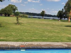 a park with a field of grass and a body of water at Lions Rest on Vaal River in Vanderbijlpark