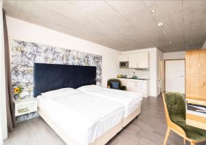 a bedroom with a large white bed and a kitchen at Tailormade Hotel IDEA Spreitenbach in Spreitenbach
