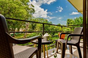 a balcony with chairs and a table with a view of trees at Tamarindo Sunshine in Tamarindo