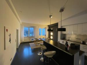 una cocina con encimera negra y sillas. en TruRetreats Design Loft I Riesige Küche I Wallbox I 65z SmartTV I 150qm, en Hamburgo