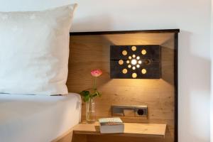 フューゲンにあるLottis Dahuamの時計が置かれたベッドと、テーブルの上に置かれた花瓶と花