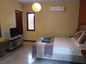Dormitorio con cama, escritorio y TV en Pipa Zen Guest House, en Pipa
