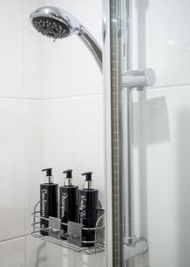 a shower with four black shampoo bottles on a shelf in a bathroom at Meldrums Apartments in Ceres