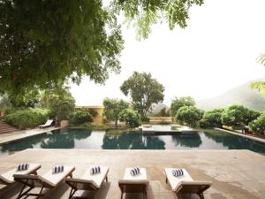 a swimming pool with lounge chairs and a table at Club Mahindra Kumbhalgarh in Kumbhalgarh