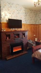 a living room with a brick fireplace with a flat screen tv at Hunters Hotel in Queenstown