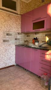 a kitchen with purple cabinets and a microwave at Квартира в Агудзере in Agudzera