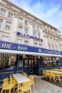 a bar with tables and chairs in front of a building at La Marinière Hôtel Restaurant in Saint Malo