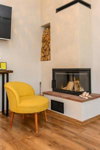 a living room with a yellow chair and a fireplace at The Good House - Harman in Hărman