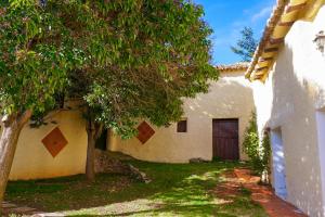 a house with a tree and a building with a door at Masía Finca La Sazadilla con Piscina in Albentosa