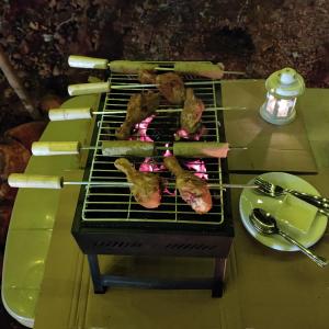 a grill with meat and tongs cooking on at Exotic Stay - a unique experience in Pune