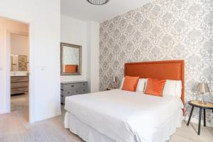 um quarto com uma grande cama branca com almofadas laranja em Apartments Olé - Tetuán em Sevilha