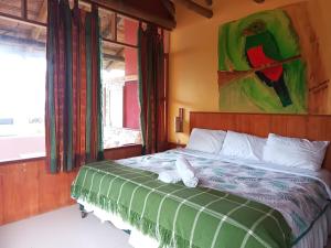 1 dormitorio con 1 cama con una pintura en la pared en Biohostal Mindo Cloud Forest en Mindo