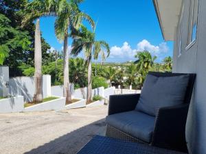 a blue couch sitting on a porch with palm trees at Studio Apartment Volterra Curacao in Willemstad