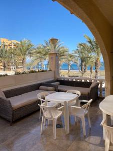 een patio met een bank, tafels en palmbomen bij Bungalow en Arenales del Sol in Arenales del Sol