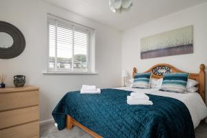 a bedroom with a large bed with a blue blanket at Rivage - Modern Maisonette in Deganwy