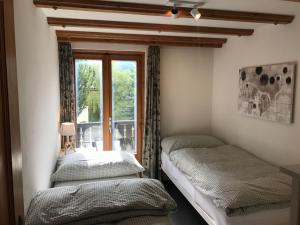 two beds in a room with a window at Chasa Tusa 2 in Scuol