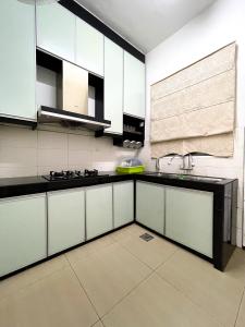 une cuisine avec des armoires blanches et des comptoirs noirs dans l'établissement Muslim Homestay Raudhatul Jannah Bandar Sri Sendayan, à Seremban