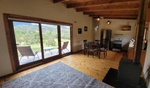 sala de estar con ventana grande, mesa y sillas en Turismo y Cabañas Dragon de La Patagonia, en Cochrane