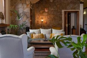 a living room with a couch and a stone wall at Hotel El Tejar & Spa in Vilaflor