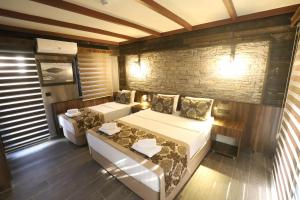 a bedroom with two beds and a brick wall at SARIGERME NEW GATE HOTEL in Sarigerme