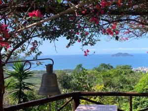 a bell on a fence with a view of the ocean at Aruna espaco regenerativo in Florianópolis