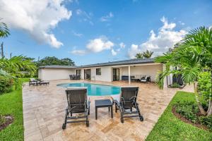 a backyard with a pool and chairs and a house at Sandals Beach Cottage in Fort Lauderdale