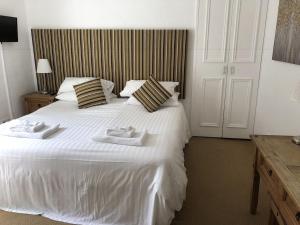 a bedroom with a large white bed with two towels on it at The Sun Rooms in Alnmouth