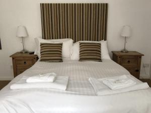 1 cama blanca grande con 2 toallas en The Sun Rooms en Alnmouth