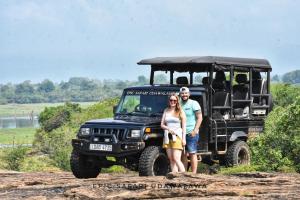 Un uomo e una donna in piedi davanti a una jeep di Forest Edge Safari Villa a Udawalawe