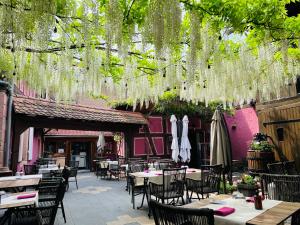 an outdoor restaurant with tables and chairs and hanging plants at Auberge Le Meisenberg in Châtenois