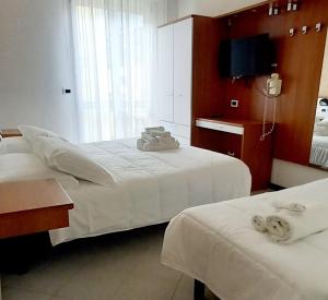 a hotel room with two beds and a television at Hotel Brotas in Rimini