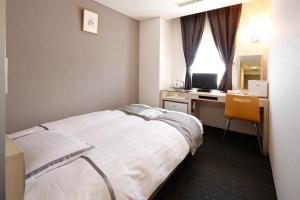 a hotel room with a bed and a desk with a computer at KOKO HOTEL Numazu Ekimae in Numazu