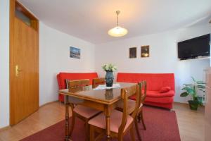 comedor con mesa y sillas y sofá rojo en Apartments Fejer, en Njivice