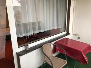 a red table and a chair next to a window at Hotel Saarland Lebach in Lebach