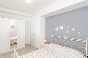 a white bedroom with a bed and a mirror at Sea view apartment 10 minutes walk from old city in Dubrovnik