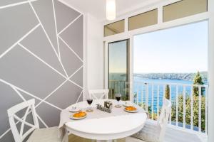 a white dining room with a table and a large window at Sea view apartment 10 minutes walk from old city in Dubrovnik
