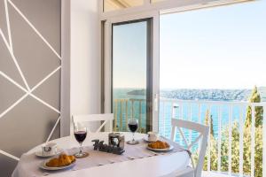 a dining table with two glasses of wine and a large window at Sea view apartment 10 minutes walk from old city in Dubrovnik