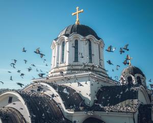a flock of birds flying in front of a church at Hotel Omni in Valjevo