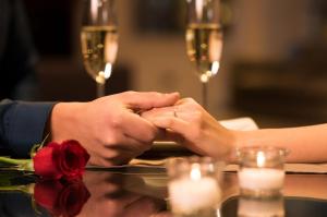 a couple holding hands while sitting at a table with wine glasses at Knaus Apartments in Chernivtsi