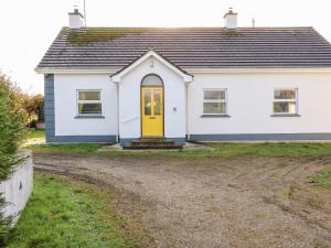 a white house with a yellow door on a dirt road at 17 Buninver Road in Omagh