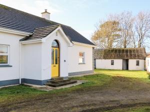 uma casa branca com uma porta amarela em 17 Buninver Road em Omagh