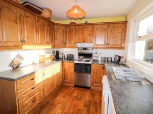 La cuisine est équipée de placards en bois et d'un four avec plaques de cuisson. dans l'établissement 17 Buninver Road, à Omagh