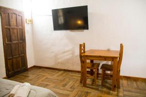 Habitación con mesa y TV en la pared. en Tacuifi I - Apartamentos en Los Reartes