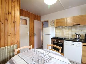 a kitchen with a table and a white refrigerator at Chalet au Mont-Dore, 300m du centre, 6 pièces, garage, terrain pentu, idéal 8 pers, animaux non acceptés. - FR-1-608-4 in Le Mont-Dore