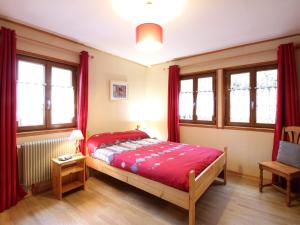 a bedroom with a bed with red sheets and windows at Chalet au Mont-Dore, 300m du centre, 6 pièces, garage, terrain pentu, idéal 8 pers, animaux non acceptés. - FR-1-608-4 in Le Mont-Dore
