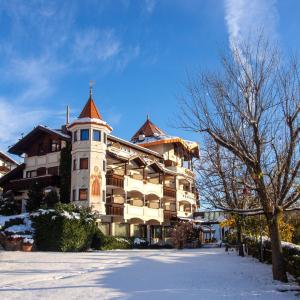 ein großes Gebäude mit einem Turm oben im Schnee in der Unterkunft Granpanorama Hotel StephansHof in Villanders