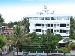 a white building with palm trees in front of it at Hotel GreenLand-Elegant in Kolhapur