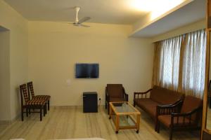 een woonkamer met een bank en een tv aan de muur bij Hotel GreenLand-Elegant in Kolhapur