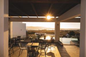 un patio con mesas y sillas en el balcón en Kouros Blanc Resort & Suites en Pounda